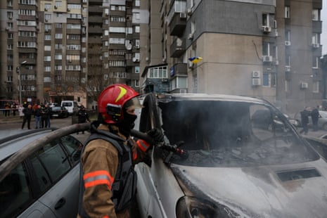 Emergency workers extinguish fire in vehicles at the site of a Russian missile strike in Kyiv.