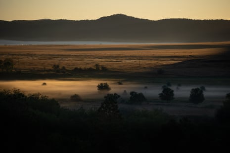 A photo of the Mora Valley landscape at sunrise with fog in the foreground and mountains in the background