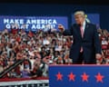 Donald Trump points toward a cheering crowd holding American flags at a campaign rally