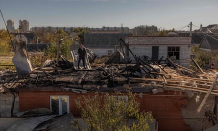 A man stands on a roof of a house in Kherson that was damaged during a Russian attack