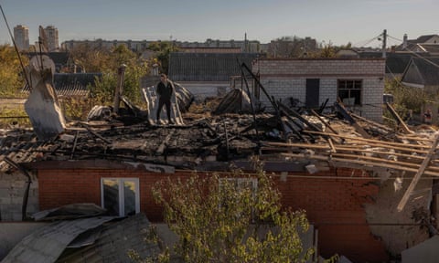 A man stands on a roof of a house that was damaged during an overnight Russian attack, in the southern city of Kherson, 30 October, amid the Russian invasion of Ukraine.
