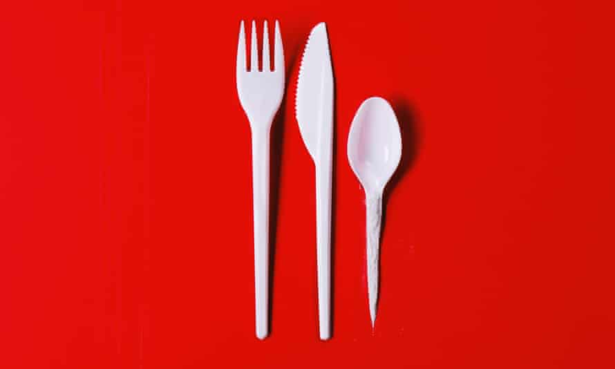White plastic fork, knife and spoon with cocaine along the handle, against red background