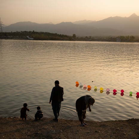 Two men and two small children at the edge of a lake