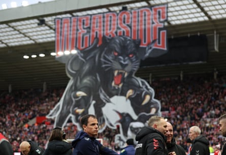 Régis Le Bris stands pitchside before Sunderland’s game against Newcastle, with a giant fans’ tifo in the background.