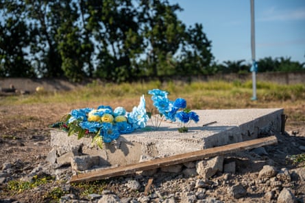 A concrete slab headstone with pale blue flowers resting on it