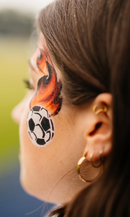 A woman with a small soccer ball painted on her face