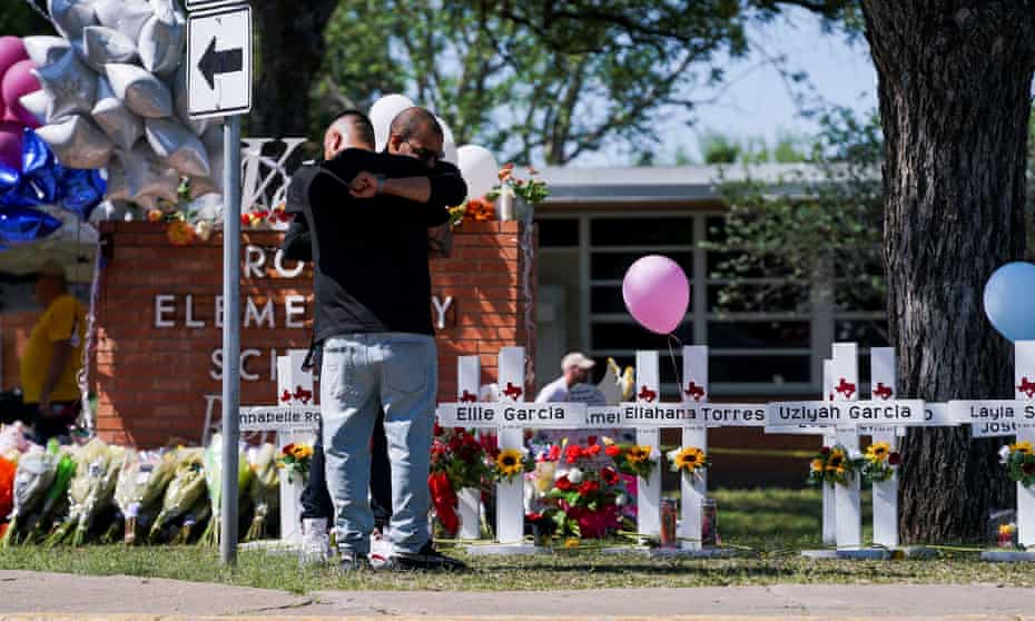 People mourn in front of memorial crosses for the victims of the mass shooting in Uvalde, Texas.