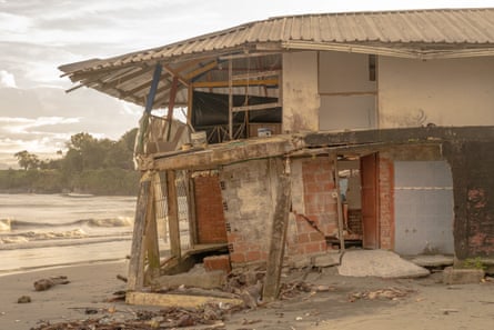A collapsing house on a beach near the water’s edge