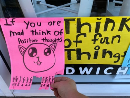 A pink poster reads “If you are mad think of positive thoughts” above a drawing of a cat. The yellow poster next to it reads “Think of fun things”.