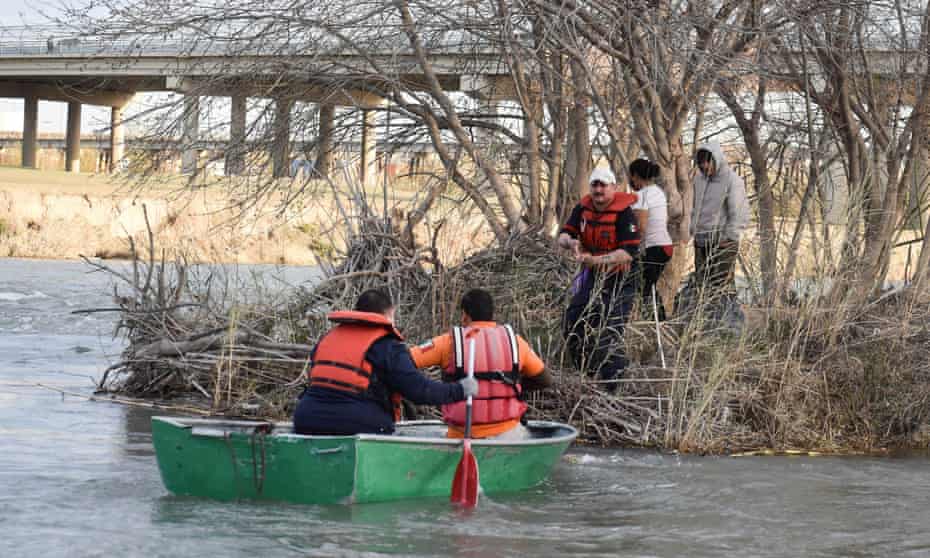 A Mexican paramedic helps a family from Honduras, stranded while trying to cross the frigid waters of the Rio Grande river from Mexico into the US, in Piedras Negras on Wednesday. 