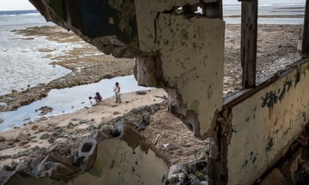 Children play near the remains of a house in Jenrok that was destroyed by the sea.