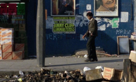 a schoolboy walks down a littered street in ladbroke grove, london, in the 1970s