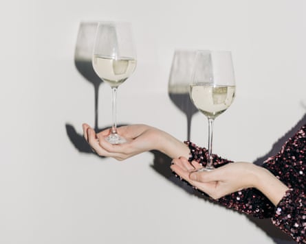 Young woman hand with two glasses of champagne on white wall background, harsh light