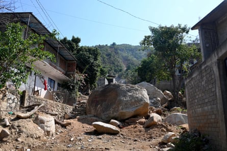 Huge boulders sit between houses on a dusty path