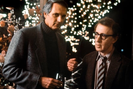 Alan Alda in a jacket and polo neck jumper and Woody Allen in a shirt and striped tie and jacket at a party with fairy lights behind