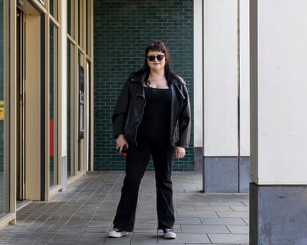 Jessica Morgan wearing sunglasses, a black jacket and black trousers stands outside a modern building.