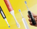 Four electric toothbrushes with bristle heads are arranged against a yellow background, one held by a hand