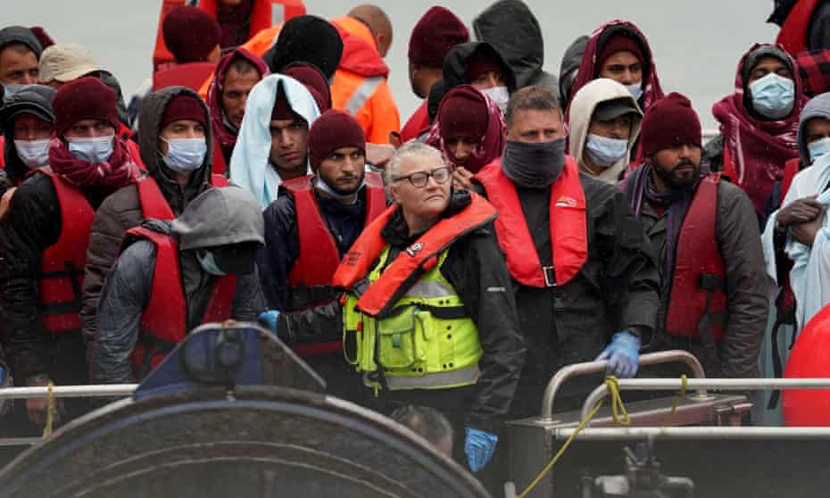 Group of people in lifejackets being brought in to Dover, Kent.
