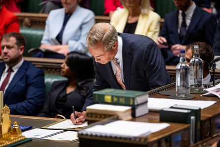Nigel Farage signs a book on a desk in the House of Commons.