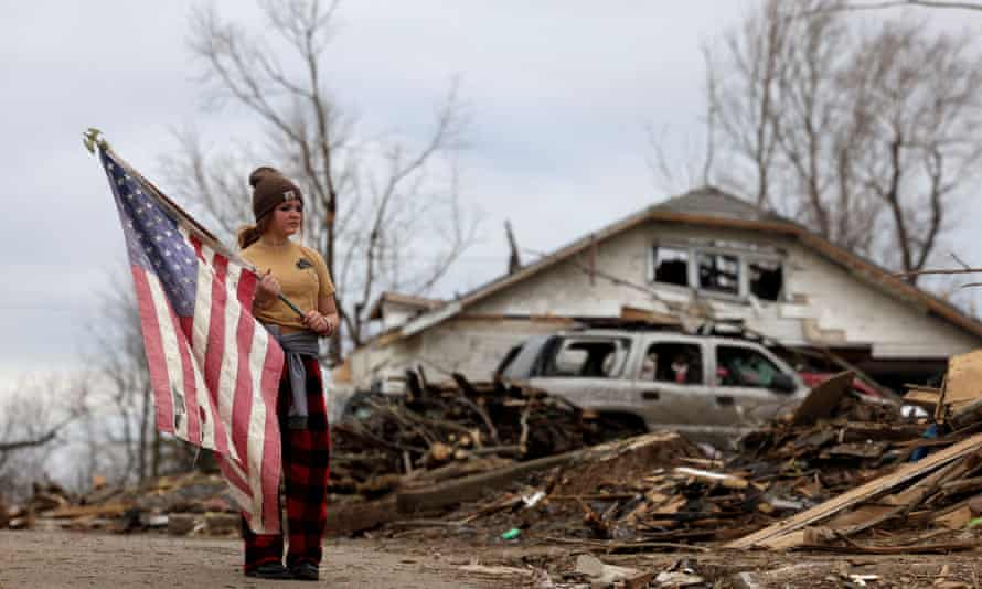 A person holds a US flag as Biden surveys damage from tornadoes in Dawson Springs, Kentucky, in December.