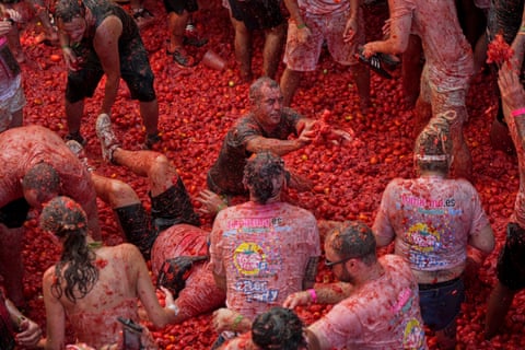 People covered in tomato pulp and juice throw tomatoes at one another.