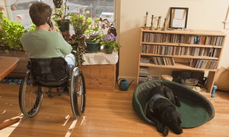 Woman with multiple sclerosis in a wheelchair talking on a mobile phone with service dog sitting near her