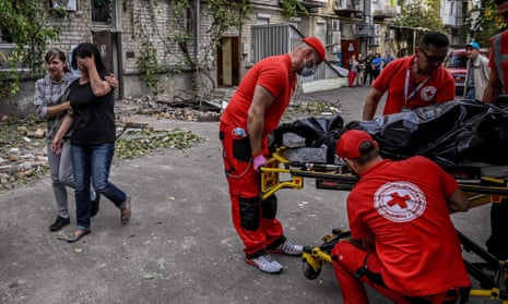 Rescuers carry a body of woman killed in a residential building which was shelled in the city of Mykolaiv on Saturday