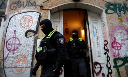 German police officers in balaclavas leave a house in Berlin