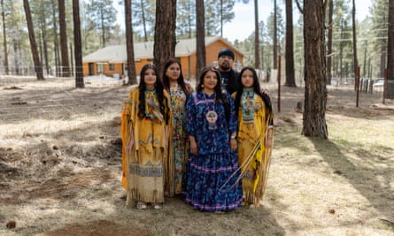family of five poses among trees near house