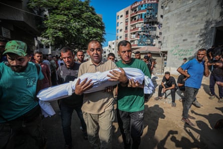 A man carries a child killed in an Israeli attack to al-Shifa hospital to be prepared for burial on Saturday.