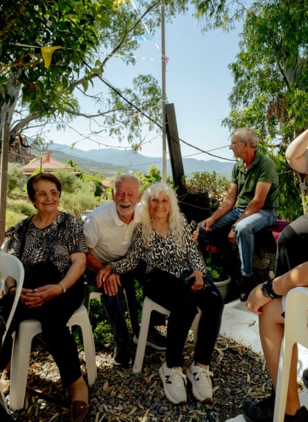 Smiling people sit in white garden chairs