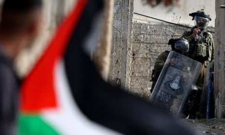 A Palestinian demonstrator waves a national flag during confrontations with Israeli troops.