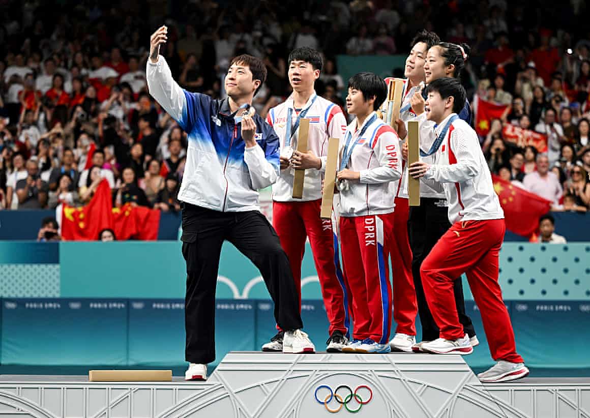 South Korea's Lim Jonghoon (L) takes a selfie picture as he celebrates on the podium with gold medalists China's Wang Chuqin (rear R) and China's Sun Yingsha (front L), silver medalists North Korea's Ri Jong Sik (2nd L), and North Korea's Kim Kum Yong (C) and bronze medallist and South Korean teammate Shin Yubin (rear R) at the end of their mixed table tennis doubles competition at the Paris 2024 Olympic Games