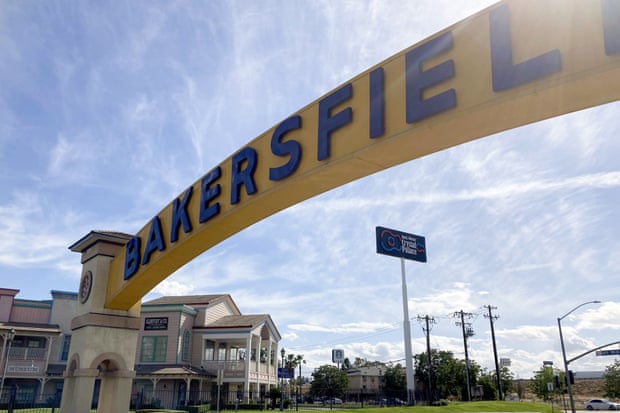 A sign for Bakersfield, California, is displayed over a city street.