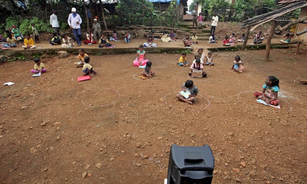 Schoolchildren take pre-recorded lessons sitting in chalk circles on the ground in Dandwal village, Maharashtra state, India.
