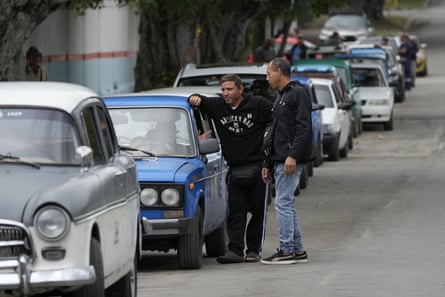 People wait in line with their cars at a gas station