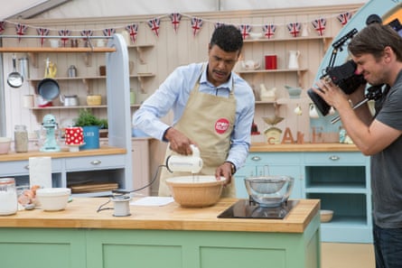 man whisking something in a bowl while a cameraman films him