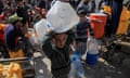 A boy holding empty plastic water containers above his head