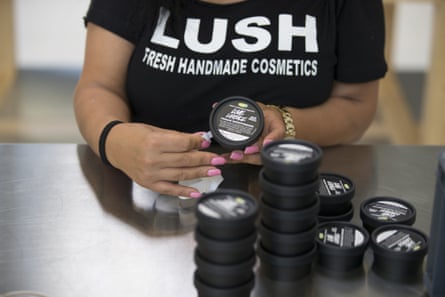 An employee labels tubs of facial scrub at a Lush factory.