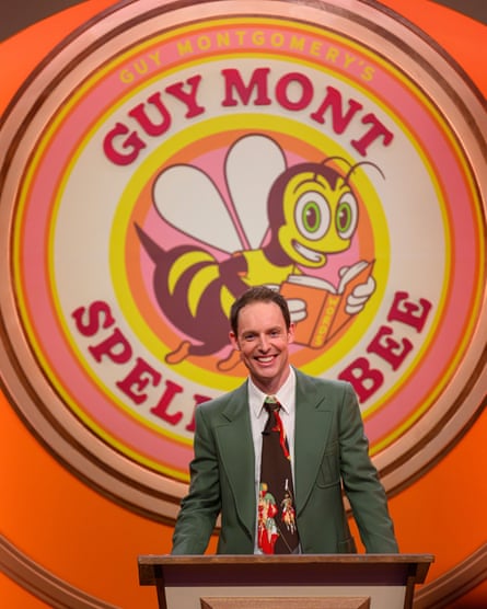 A cheery looking man in a suit and loud tie stands by a giant illustration of a bee