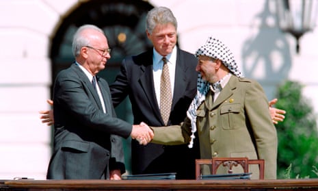 Yitzhak Rabin and Yasser Arafat shake hands as Bill Clinton gestures expansively