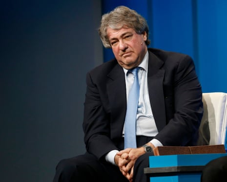 Leon Black sits in a dark suit and light blue tie, hands clasped, looking aside