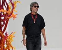 Pierpaolo Piccioli smiles in sunglasses and wears a coral necklace on the runway
