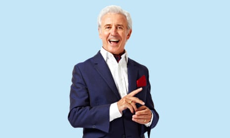 Tony Christie wearing a blue suit with a white shirt, against a pale blue background