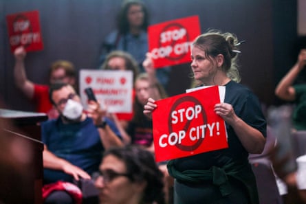 A woman holds a red sign reading ‘Stop Cop City!’ in front of a group of several others holding similar signs.