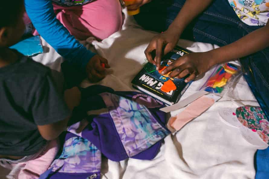 A closeup of a group of children’s hands playing with putty on a mattress.