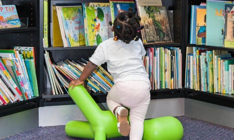 Child choses what books to read later leaning on a child chair in Harlesden library in the london borough of Brent