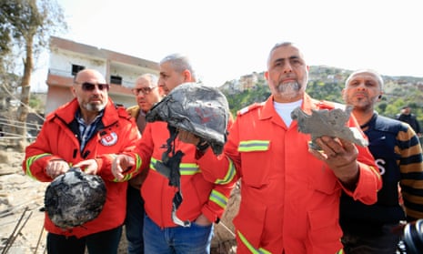 Rescuers show belongings of the victims at the site of an airstrike in Hebbariye, southern Lebanon, on 27 March.
