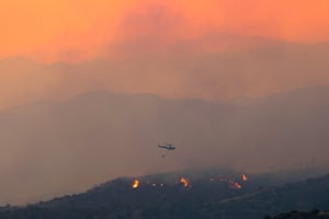 Larnaca, Cyprus: A helicopter flies over a forest fire in the mountain region.