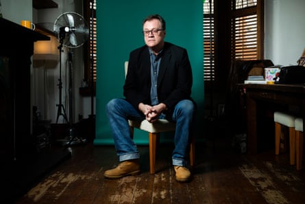 A man perched on a chair in a small dark room